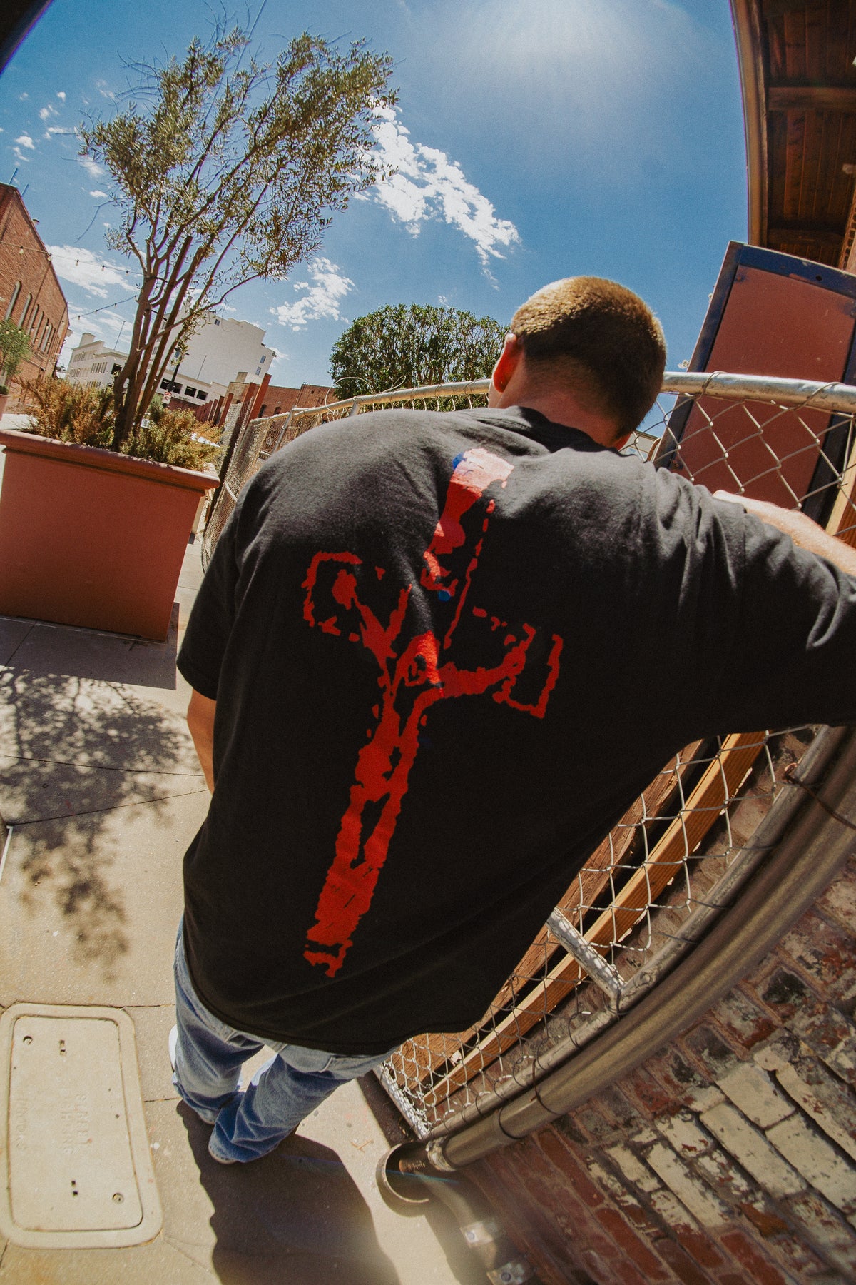 Back view of black God Is Real tee with red crucifix graphic, street style photo
