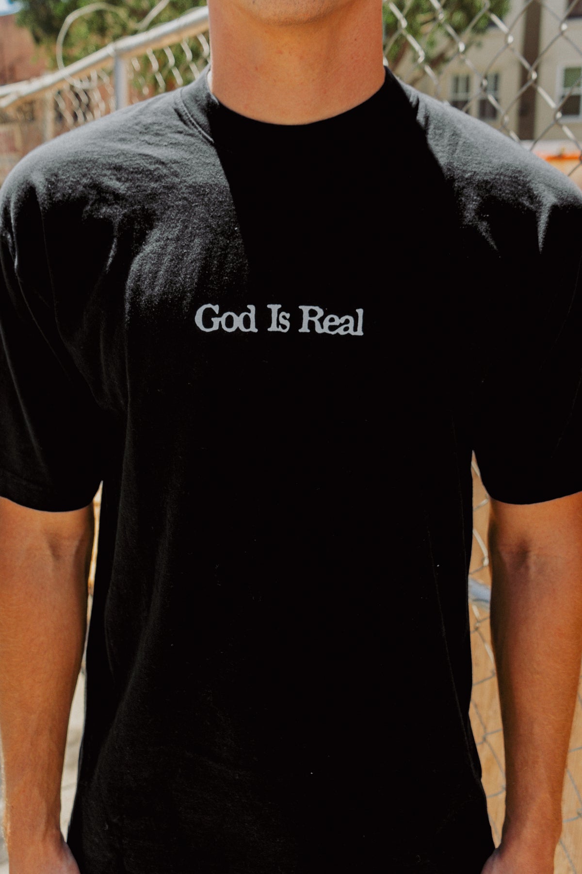 Close-up of model wearing black God Is Real Logo Tee, Christian streetwear