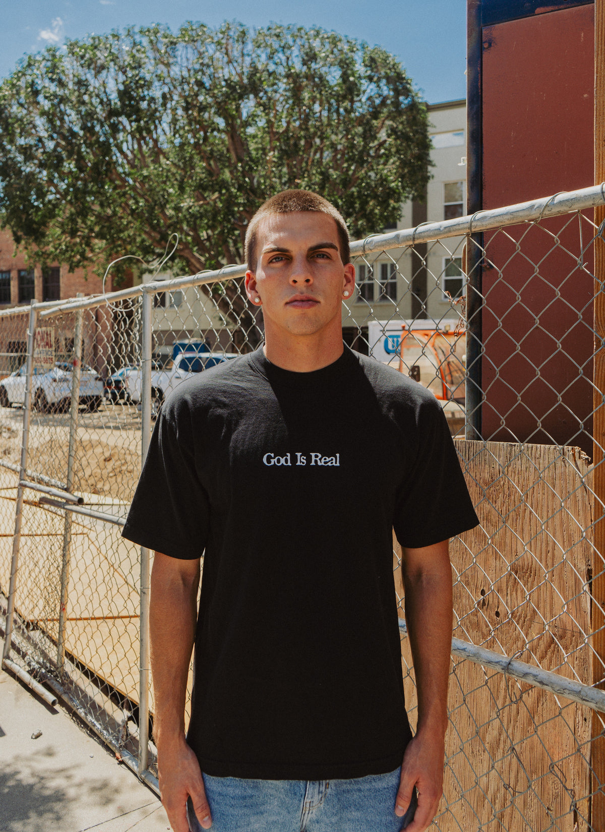 Model wearing black God Is Real Logo Tee outdoors, Christian streetwear