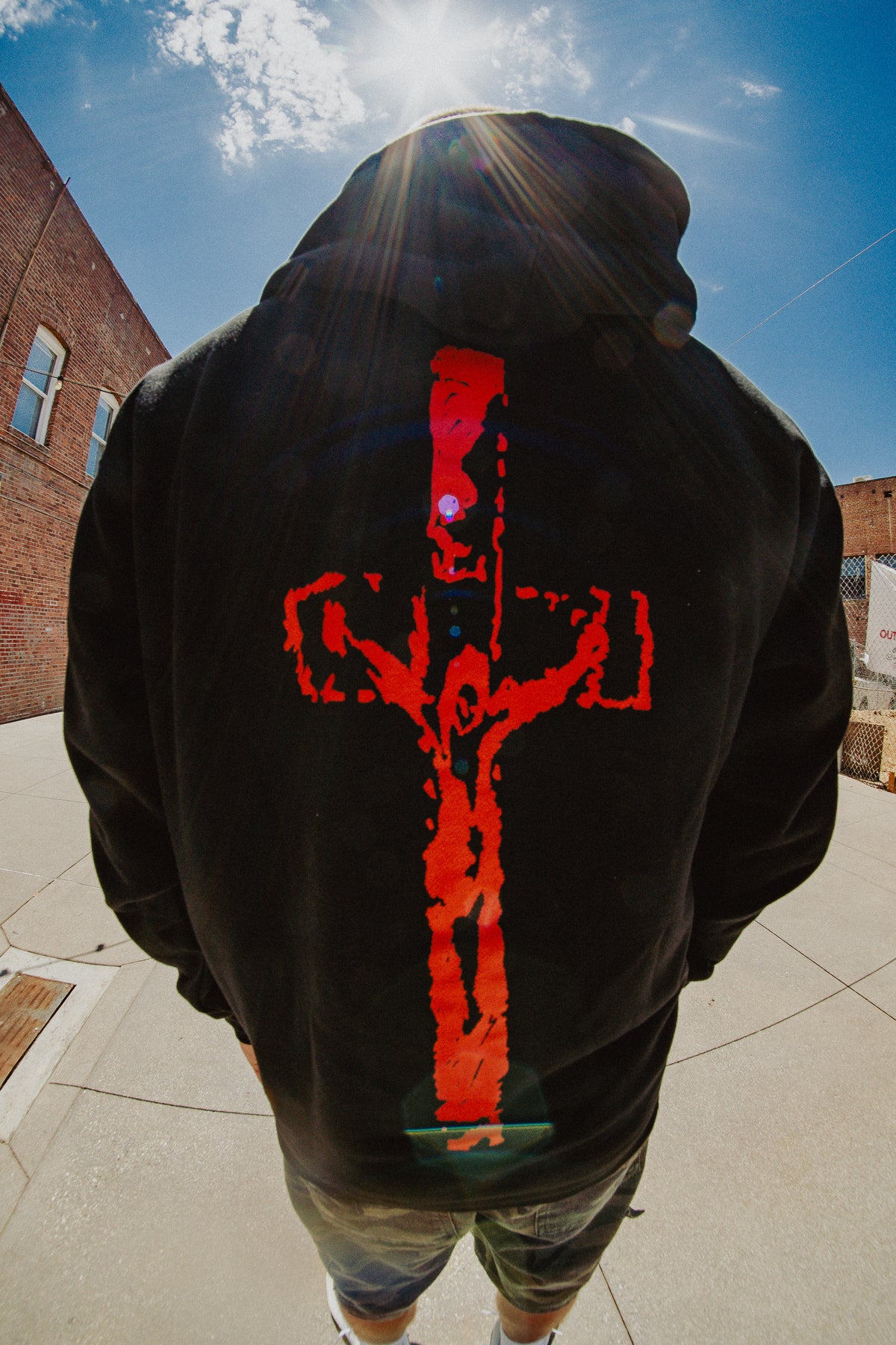 Back view of model in black God Is Real zip hoodie with red crucifix graphic