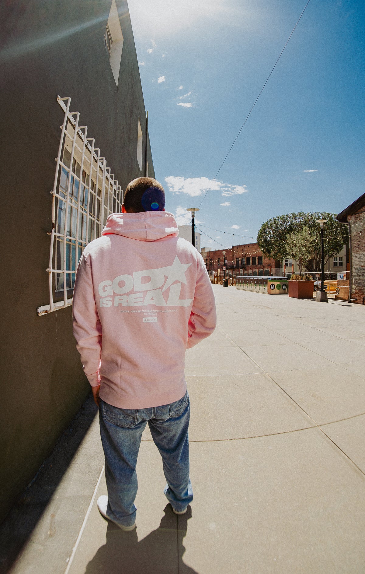 Back view of model in pink God Is Real Star Hoodie with star graphic