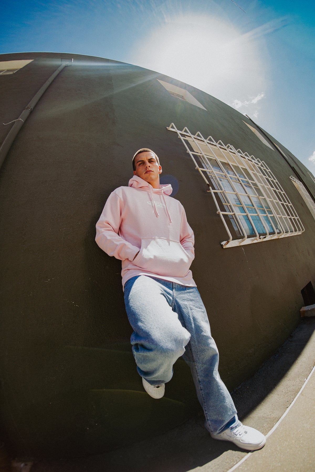 Fisheye street photo of model wearing pink God Is Real Star Hoodie